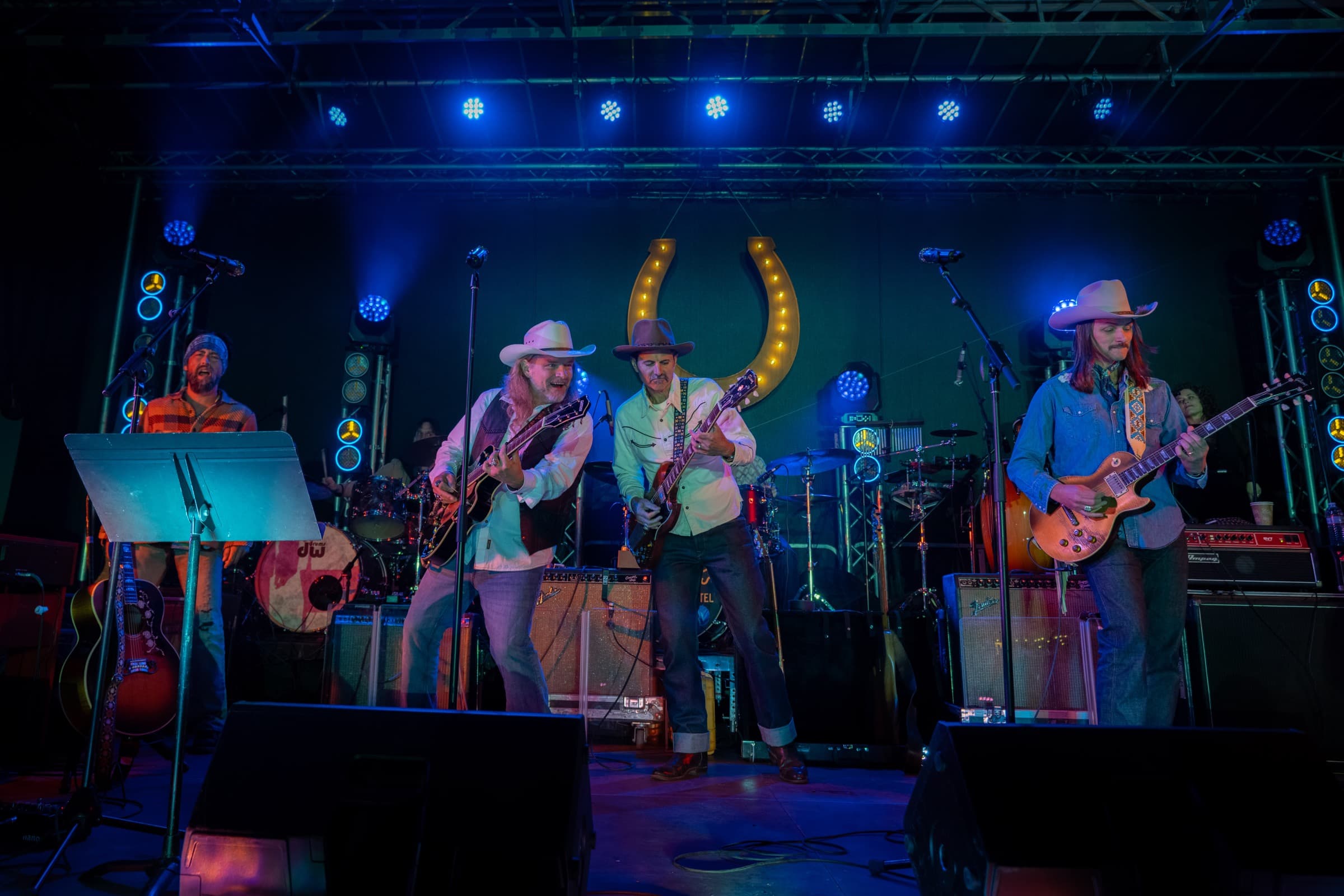 Duane Betts and his band on the Horseshoe stage under blue light, the lit horseshoe sign behind them