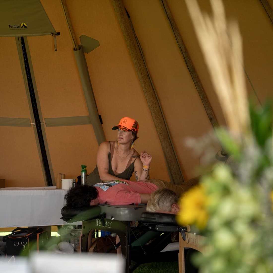 A woman working at a long table inside a tipi, herbs and produce laid out in front of her