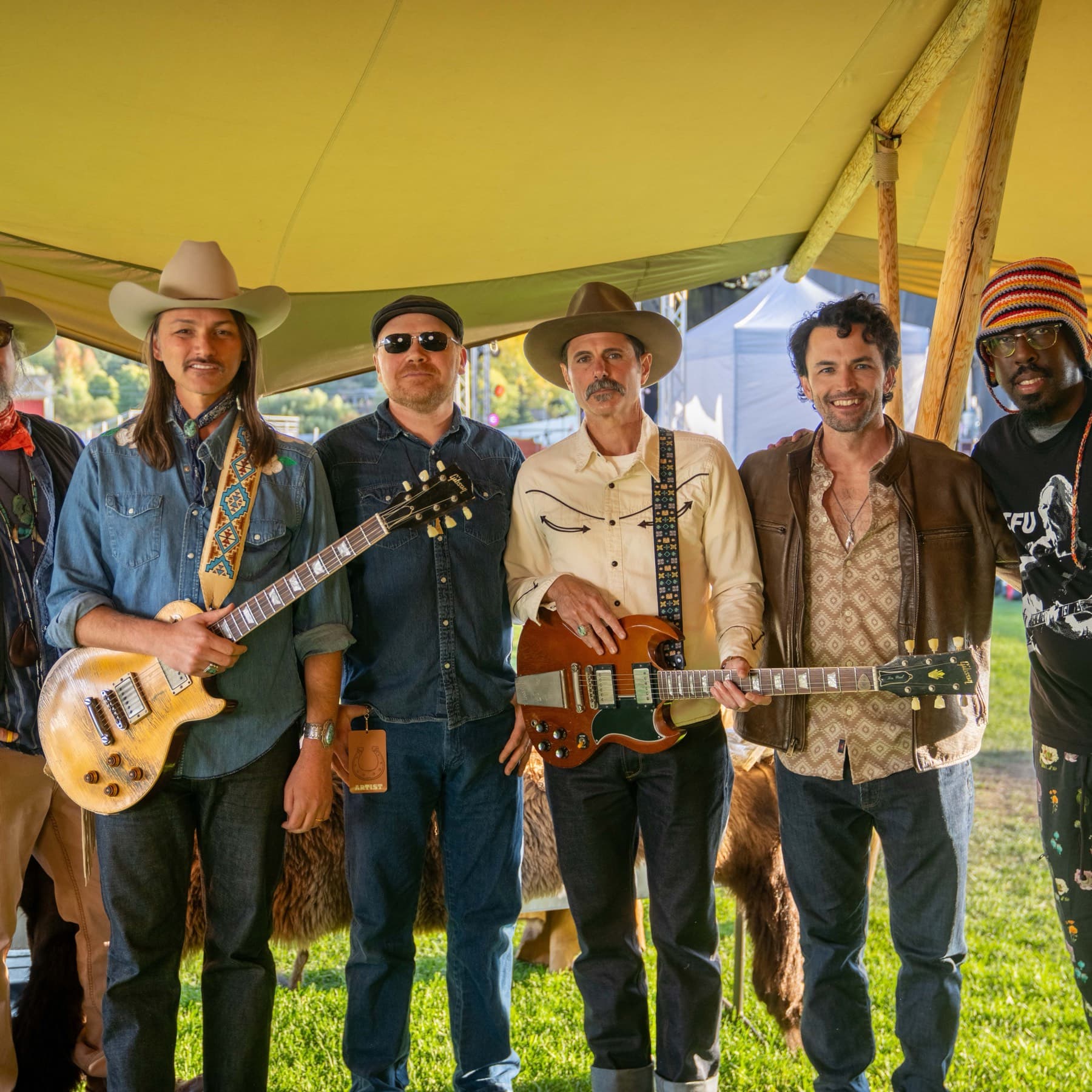 The Horseshoe family band lined up together under a tent on the grass, instruments in hand