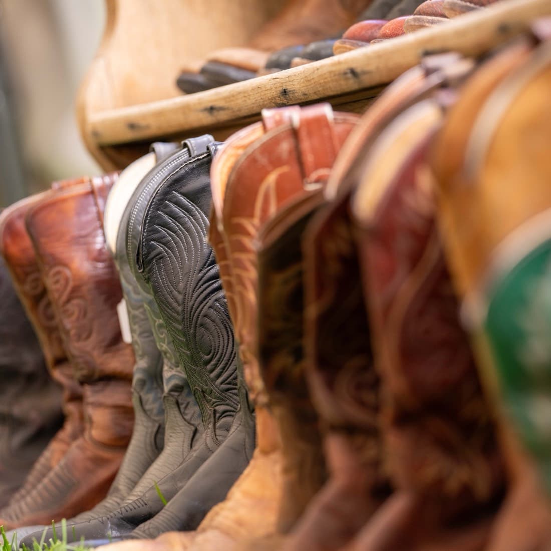 A row of tooled cowboy boots lined up on a market shelf