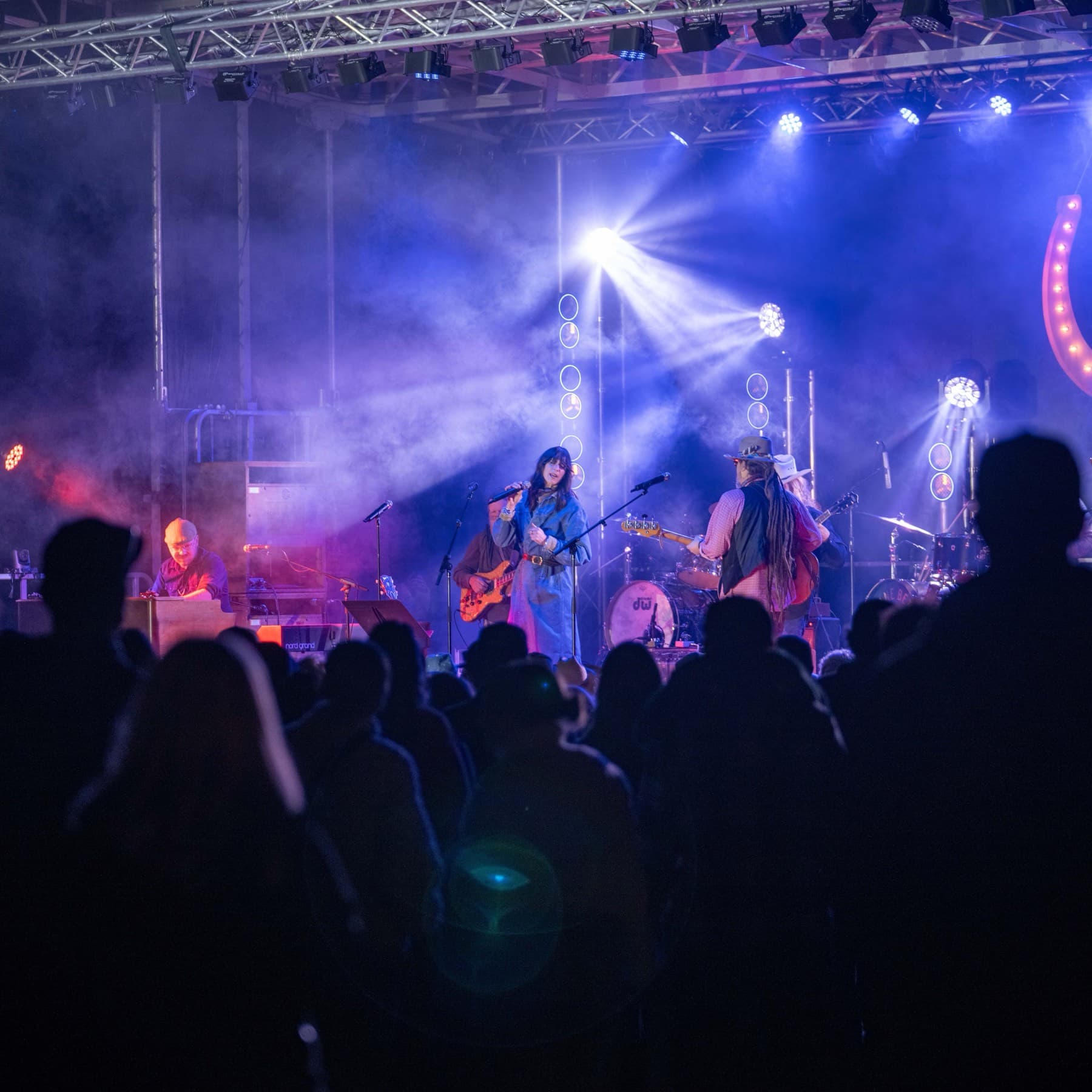 The crowd in silhouette against the stage, beams of blue light above the band