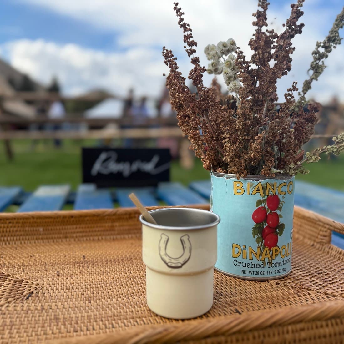 Dried flowers in a stoneware jug on a woven table runner, a horseshoe stamped on the mug beside it