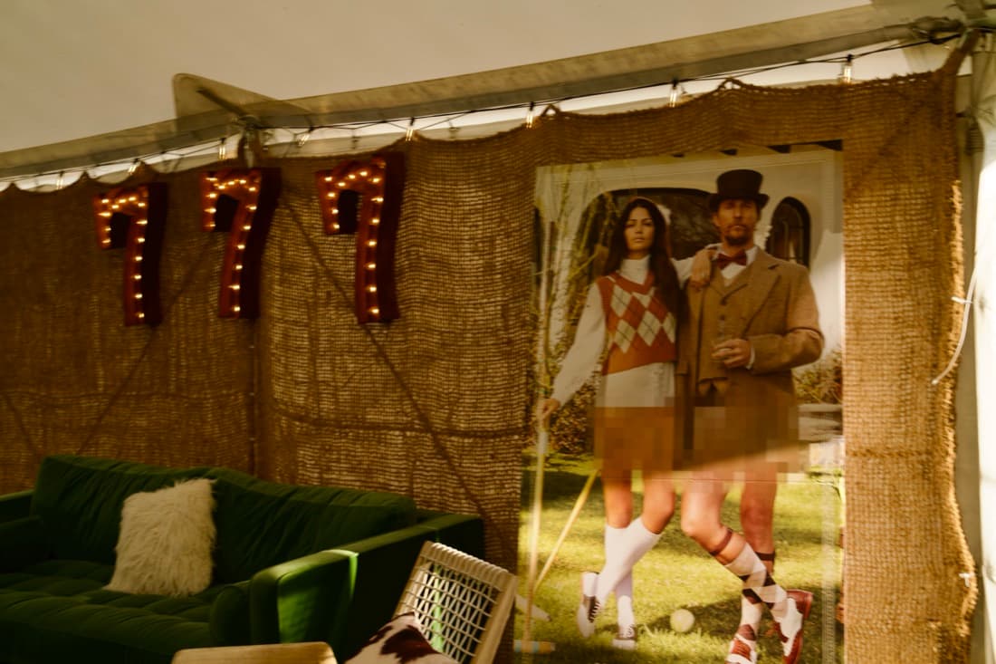 The inside of a lounge tent, low couches and rugs under strings of light